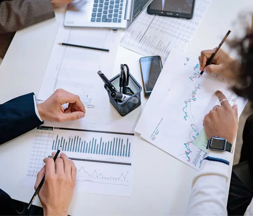 A group of people gathered around a table with spreadsheets